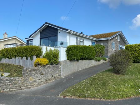 A house with a driveway and green bushes on a lawn at Seascape Hope Cove