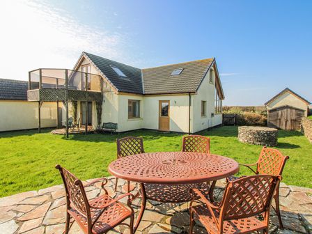 An outdoor area with a house and a round table with chairs at The Station in Bolberry