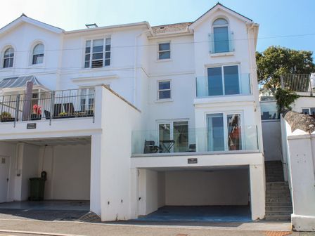 A white multi story building with balconies and open garages at Yardarm in Salcombe