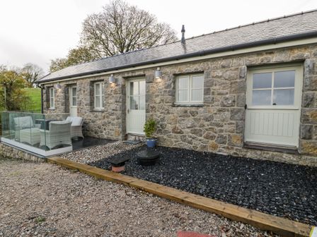 A stone exterior of a house with glass balcony and outdoor seating at Bryn Goleu in Llandudno