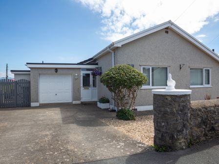 A single story house with a garage and a driveway at Cororion Cottage in Tyn-y-Gongl near Benllech