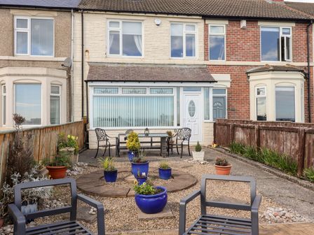 A garden area with chairs and a table at Beach Cove View in Newbiggin-by-the-Sea
