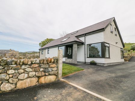 A house with a stone wall and driveway in a rural area at Llwyd Coed Canol in Llanllyfni near Penygroes