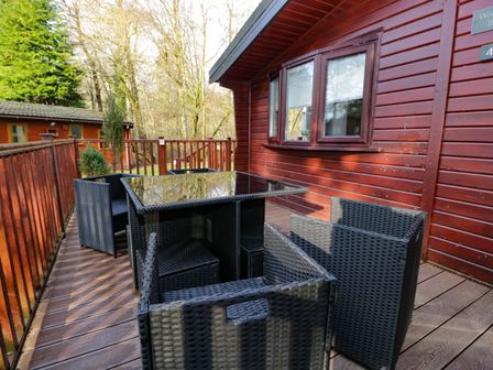 An outdoor wooden deck with a black wicker table and chairs attached to a wooden cabin at 40 Skiptory Howe in Troutbeck Bridge