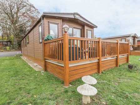 A wooden cabin with a fenced porch on a grassy lawn at 27 Lake View in Cawston