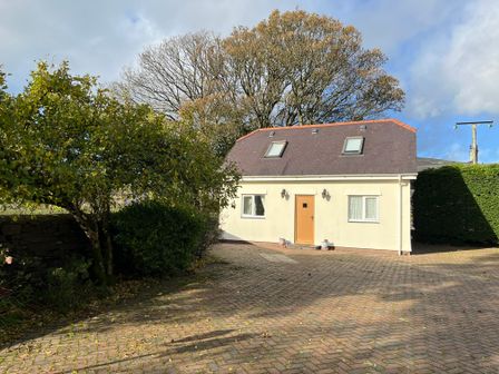 A house with a tiled roof and a driveway with trees and bushes at Meadow View in Talysarn near Penygroes