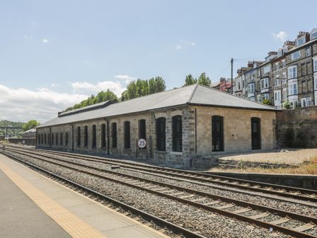 A stone building next to railway tracks and a platform at Sir Nigel Gresley @ Engine Shed in Whitby