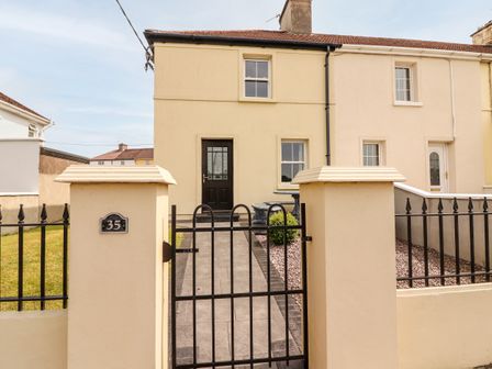 The exterior of a semi detached house with a black front door a paved pathway and a metal gate at 35 Laune View in Killorglin near Killarney