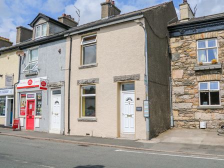 A row of buildings including a post office and a cottage with white doors on a street at Molly's Cottage in Flookburgh