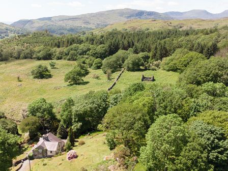 A rural landscape with a house near trees fields and hills at Cae Lleci in Llanfachreth near Dolgellau