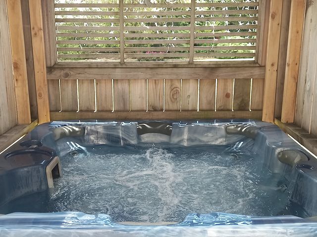 A hot tub with bubbling water inside a wooden enclosure with slatted windows at Snowed Inn - Ohakune (Miro) Holiday Home in Ohakune