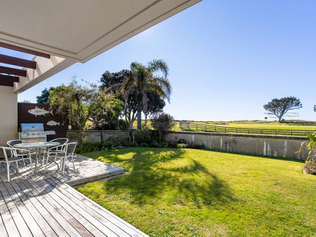 A garden area with table and chairs next to a barbecue at The Sandcastle - Papamoa Holiday Apartment in Papamoa