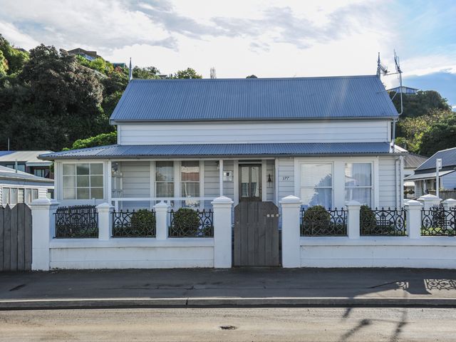 A white house with a metal roof a small front yard and a white fence with a gate at Puriri Downtown Villa Napier City