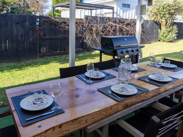 An outdoor dining area with a large table set for meals at Ronas - Whiritoa Beach Bach, Whiritoa Beach