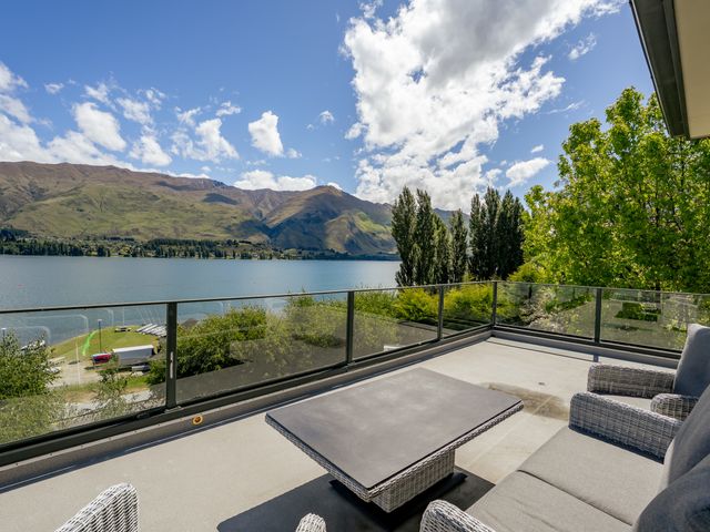 A terrace with seating area overlooking the lake and mountains at Lakeside Serenity - Wanaka Holiday Home Wanaka