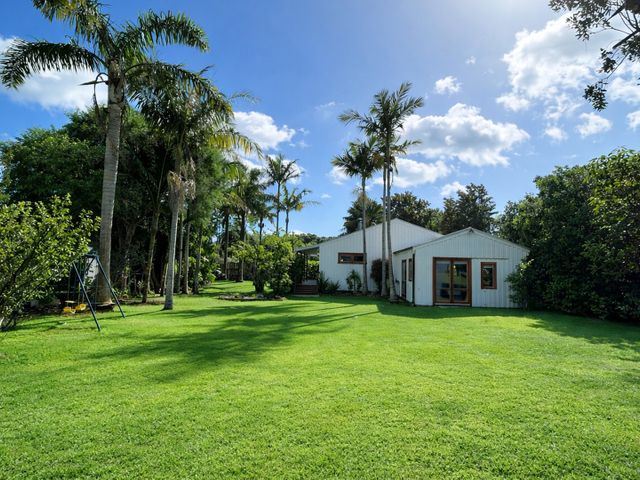 A garden with a house and palm trees at Matapouri Hideaway in Matapouri