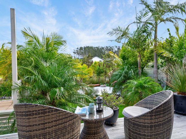 An outdoor space with chairs and a table surrounded by plants at Little Pearl of Vista Verano - Mangawhai Village