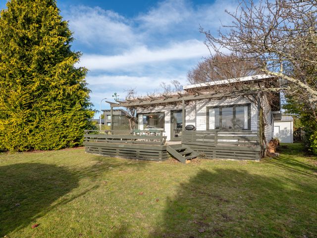 A house with a deck and outdoor seating at Wharewaka Bach - Lake Taupo Holiday Home in Wharewaka
