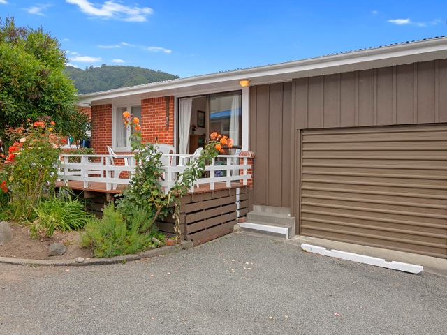 An exterior view of a house with a small deck and white chairs next to a closed garage door at The Picton Family Retreat - Picton Unit in Picton