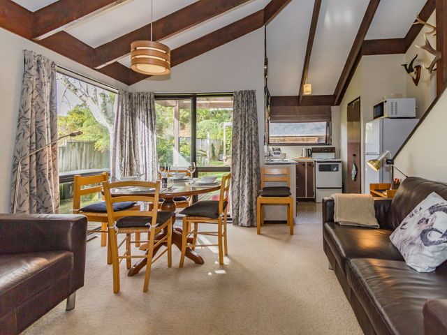 Dining area with wooden table and chairs next to a kitchen and seating area in a chalet