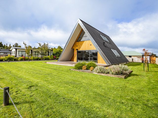 An A-frame house with a wooden deck and garden in a green lawn at Findlay Chalet - National Park Holiday Home in National Park