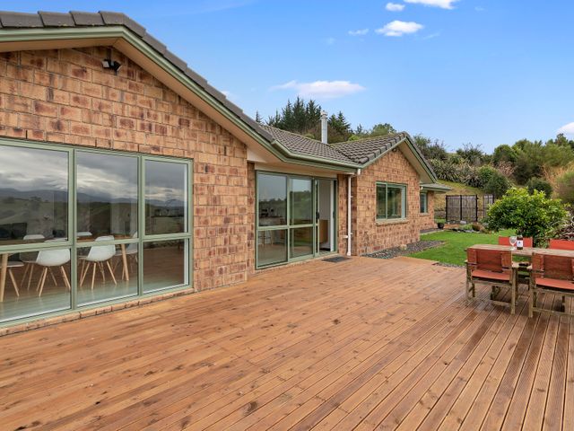 A wooden deck with outdoor furniture next to a brick house with large windows and a garden at One Two Eight - Richmond Holiday Home