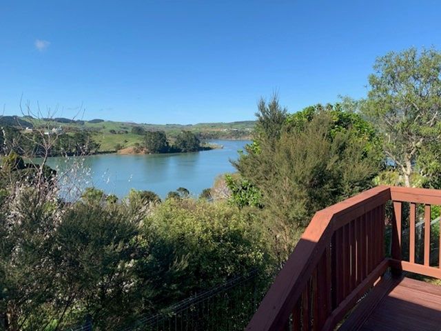 A view overlooking a body of water with trees and hills at The Shed - Raglan Holiday Home in Raglan