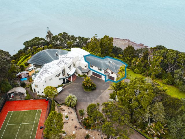Aerial view of a property with a tennis court driveway and garden near a body of water at Beachside Luxury - Laingholm Holiday Apartment in Laingholm 24km from Auckland CBD