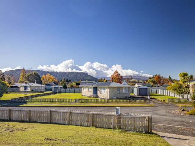 A residential neighborhood with single-story houses fenced yards and a mountain range in the background at Mountain Snow Base  Ohakune