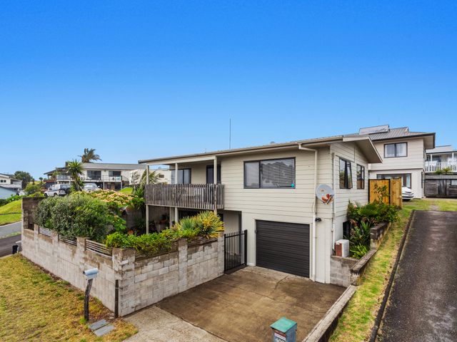 A residential house with a concrete driveway and a small garden surrounded by a block wall at Beach Close - Ohope Beach Holiday Home in Ohope Beach