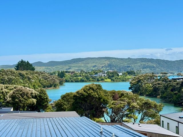 A view of water surrounded by hills and trees at Sunset Stay - Raglan Holiday Home, Raglan