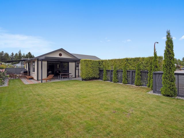 A backyard with lawn chairs a picnic table and hedges at Rangi Marie - Alexandra Holiday Home in Alexandra