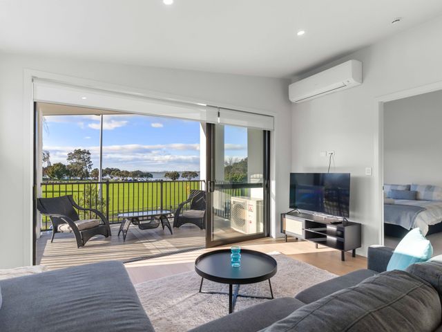 A living room with a television and sliding door at Tauranga Holiday Home in Tauranga