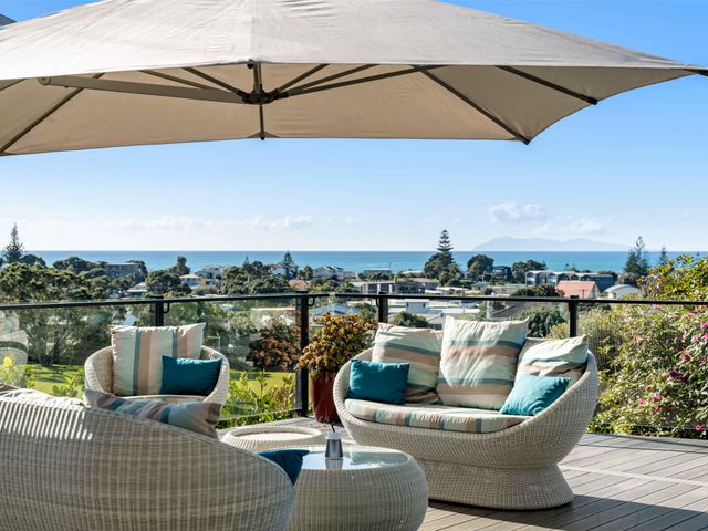 An outdoor seating area with wicker chairs and an umbrella at Island Views - Waihi Beach Holiday Home Waihi Beach