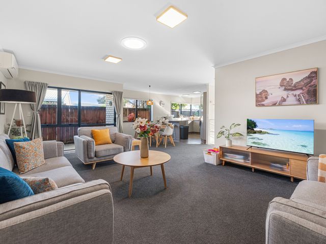 A living room with a sofa and television at Papamoa Waves - Seaside Getaway, Papamoa