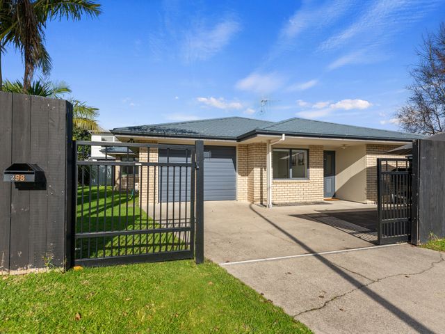 An outdoor view of a house with a gate and driveway at Papamoa Waves - Seaside Getaway in Papamoa