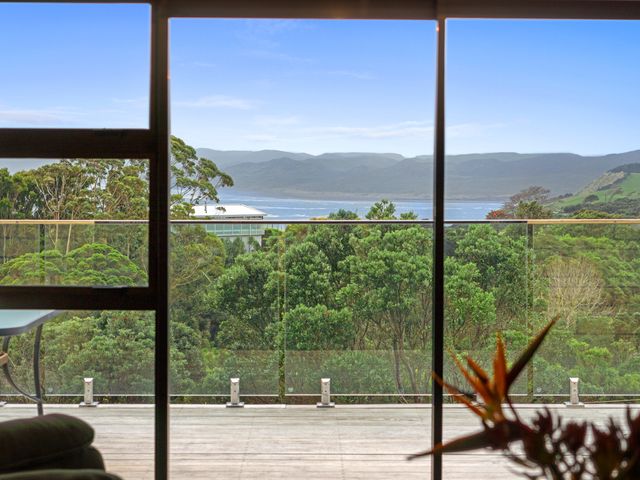 A living room with a view of trees and mountains at Raglan Holiday Home in Raglan