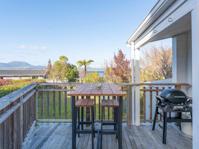 An outdoor deck with a table and chairs at The Cozy Corner - Taupo Holiday Home Acacia Bay