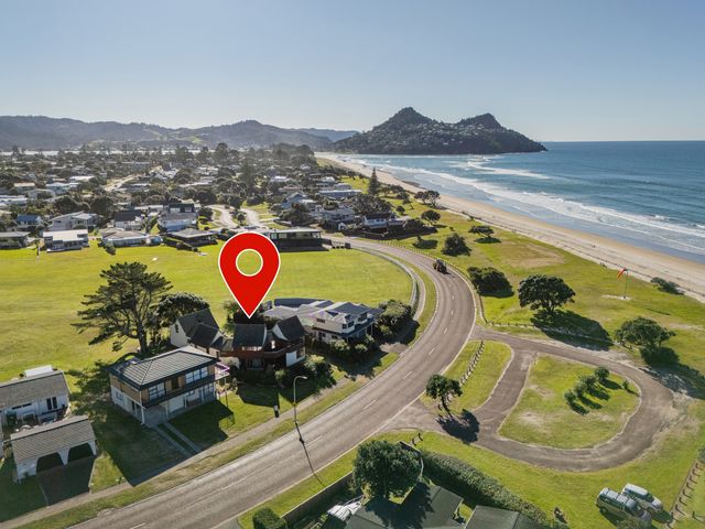 An aerial view of houses and beach at Beachfront Landing - Pauanui Holiday Home, Pauanui