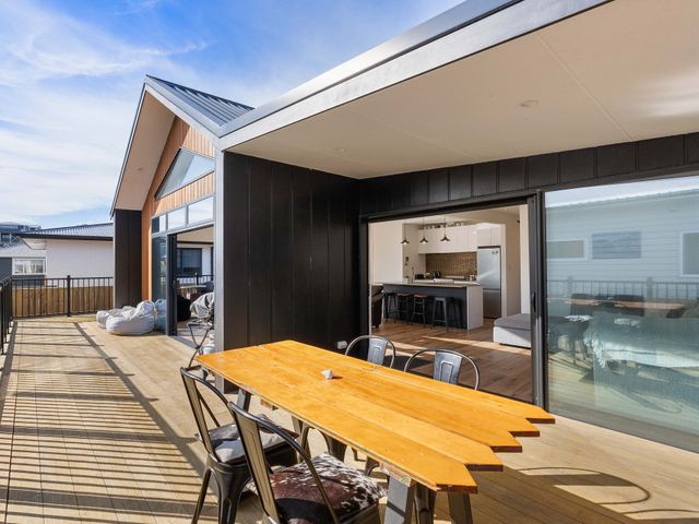 An outdoor deck with a wooden table and chairs at Waihi Beach Holiday Home in Waihi Beach