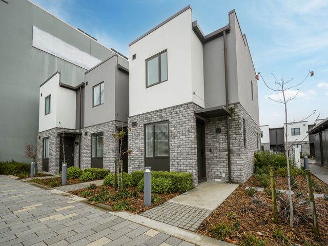 An outdoor view of modern houses with a pathway and plants at Townheart on Hereford - Christchurch City Apartment
