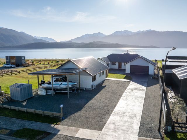 An outdoor area with a house and a boat at The Tranquil Edge - Te Anau Holiday Home Te Anau