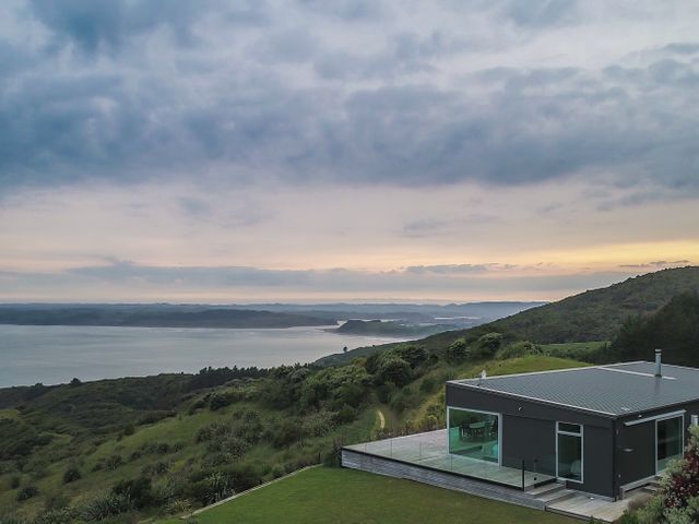 A house with a deck overlooking the ocean at The Glass House - Raglan Escape in Raglan