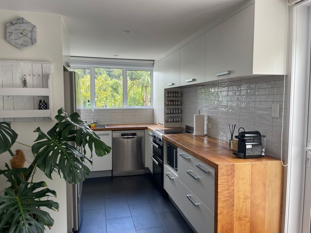 A kitchen with a sink, stove, and storage shelves at Whangarei Retreat - Whangarei