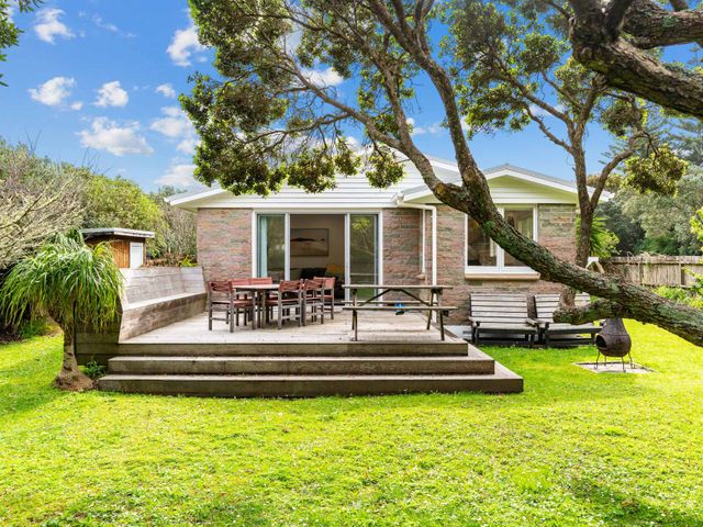 A house with a deck and outdoor furniture at Taotahi Hideaway - Ruakaka