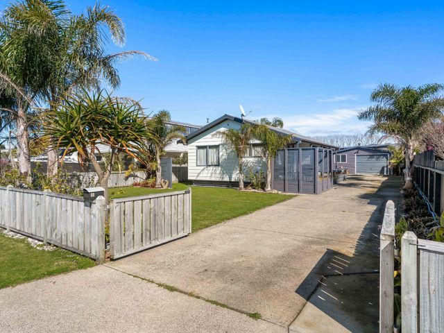 An outdoor view of a house with a driveway and garden at Whitianga Holiday Home in Whitianga