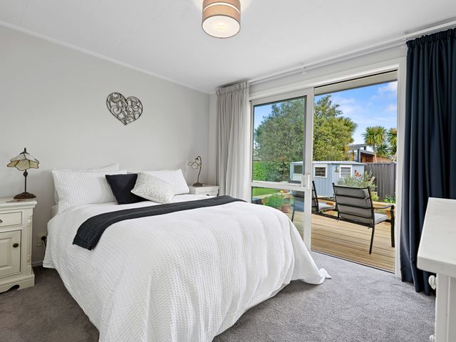 A bedroom with a bed and window overlooking a deck at Rotorua Holiday Home in Rotorua