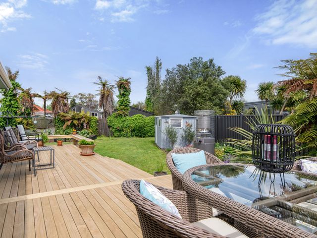 A deck area with seating and a table in the garden at Rotorua Holiday Home in Rotorua