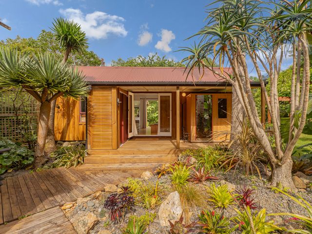 A house with plants and a wooden deck at Stream-side Cottage - Driving Creek Coromandel