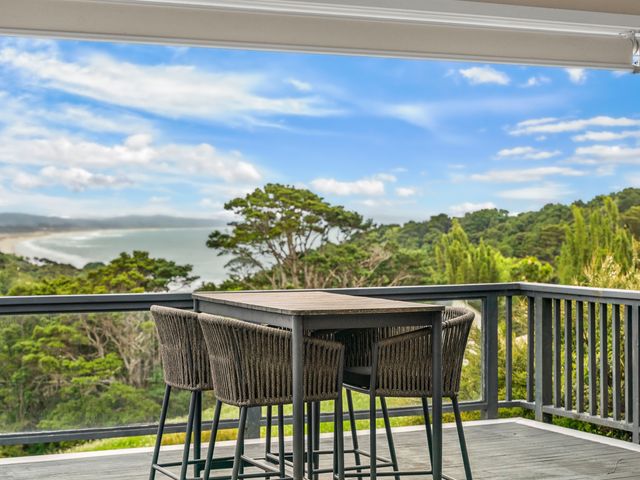 A deck with a table and bar stools overlooking a view at Waipu Holiday Home Waipu